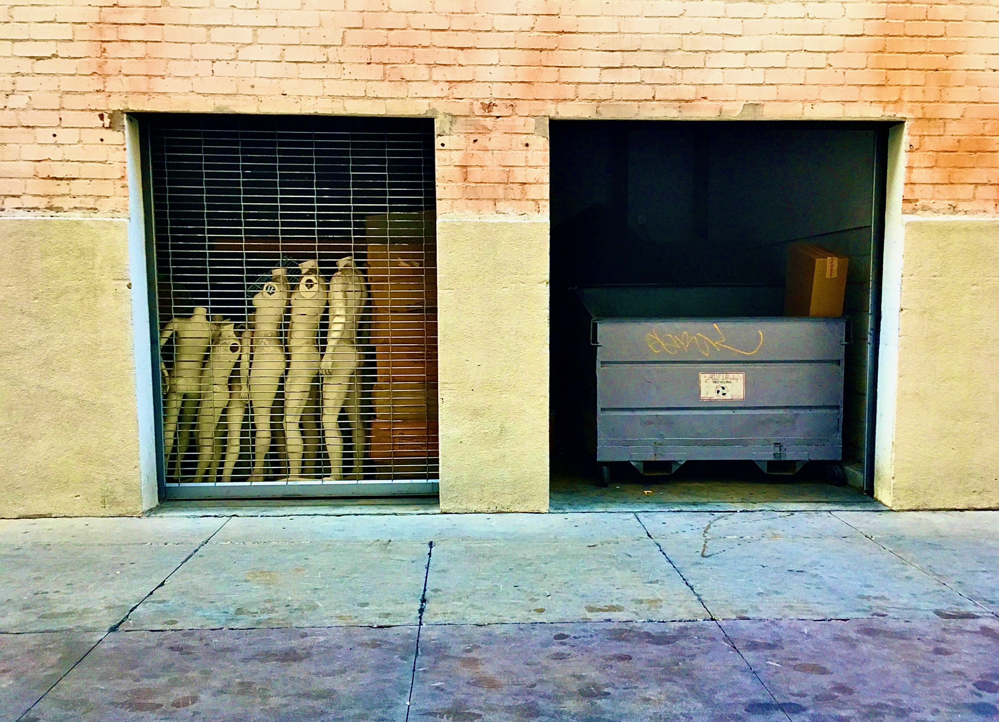 dumpster and mannequins in alley